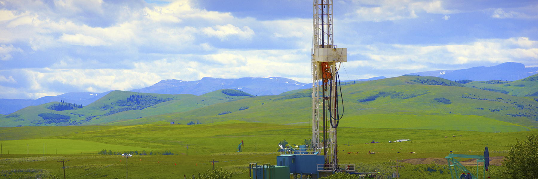 oil well in forground against scenic hills in background