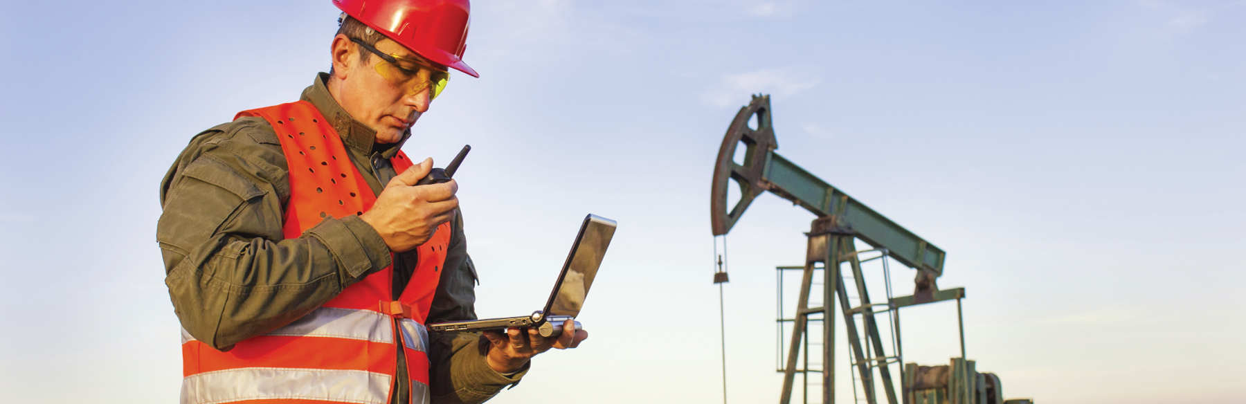 oilfield worker wearing safety equipment talking on walkie-talkie